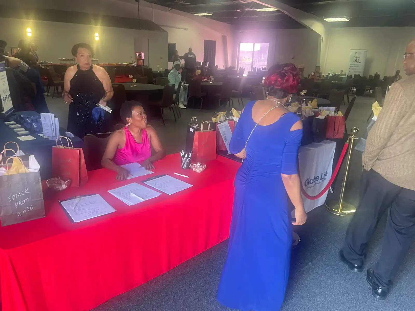 A community event table with family-planning materials, gift bags, and attendees gathered around it