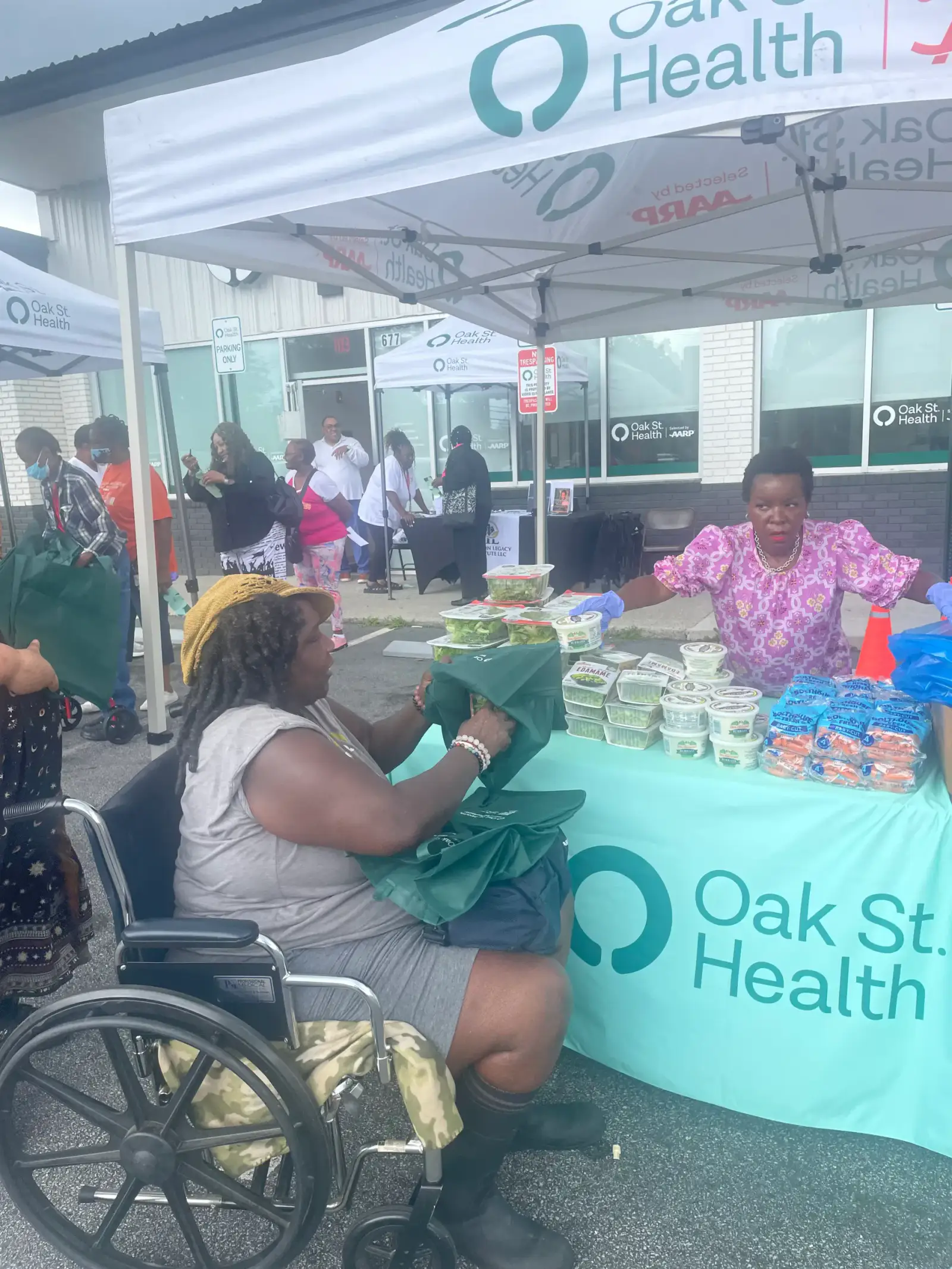 Community outreach table outside Oak Street Health with neighbors receiving food and information