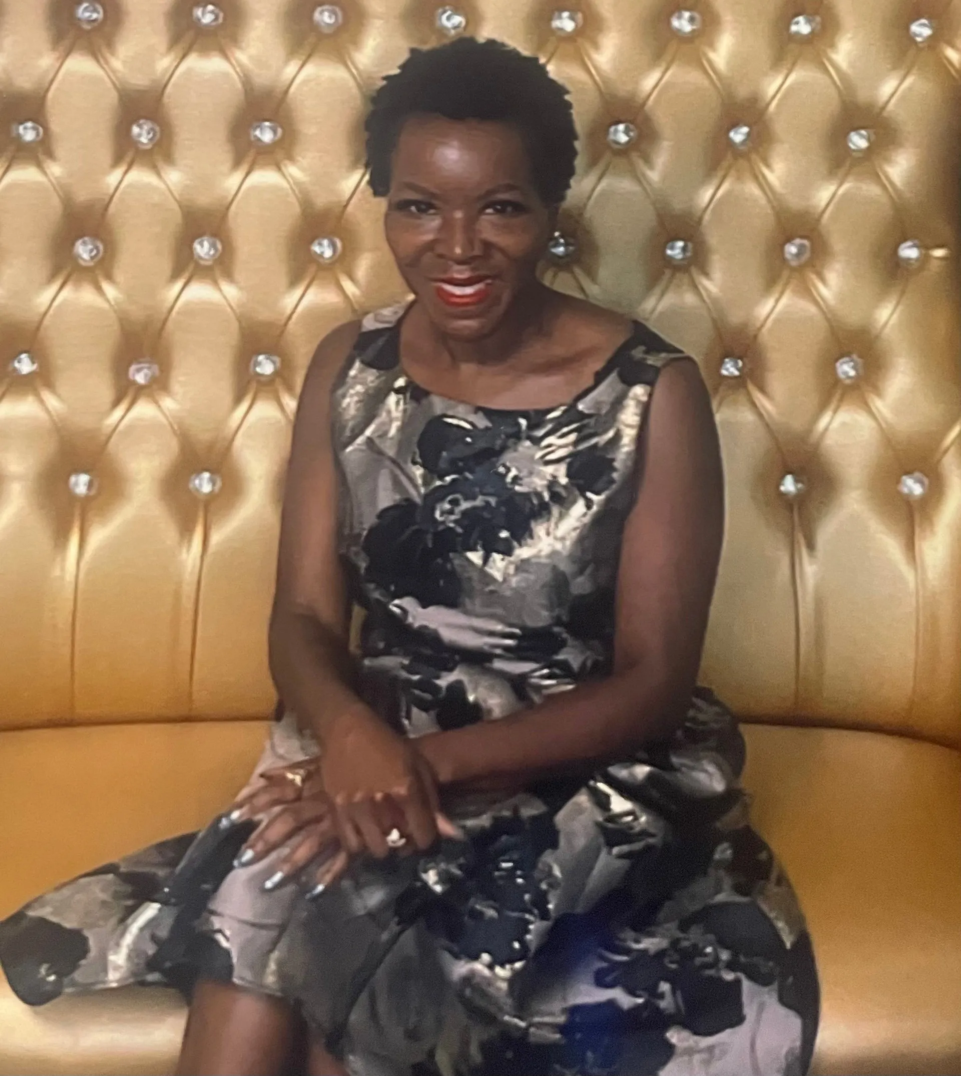Shawn Caprice Houston, founder of Houston Legacy Institute, seated in a floral dress against a gold tufted wall