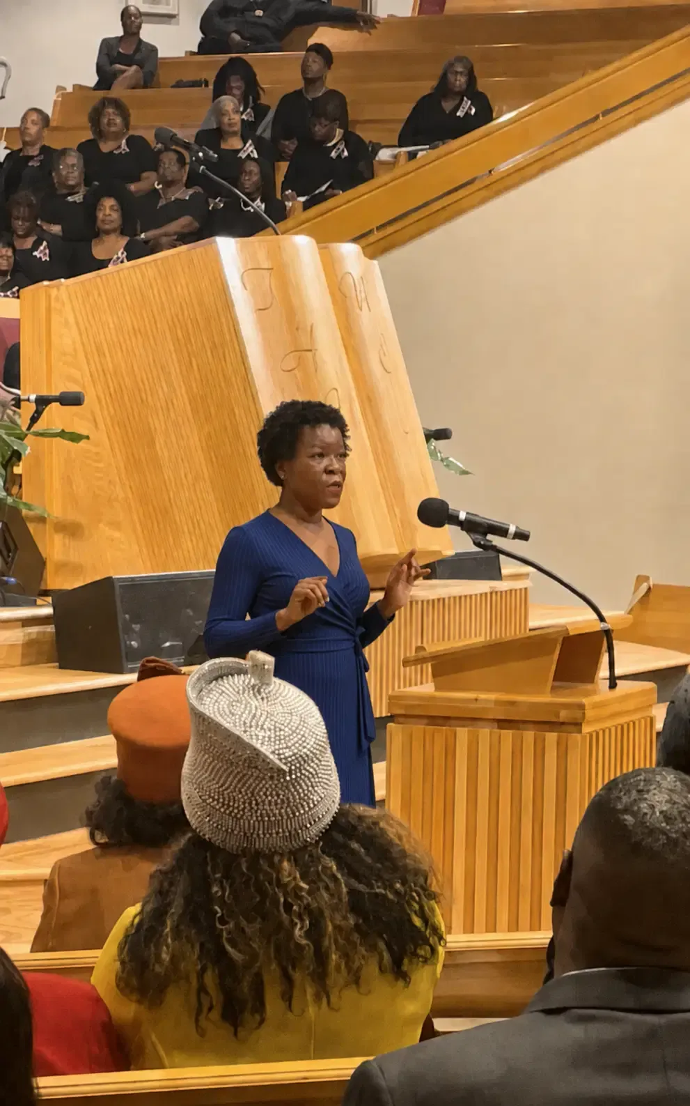 Shawn Caprice Houston speaking at a pulpit in a church with a seated community audience behind her